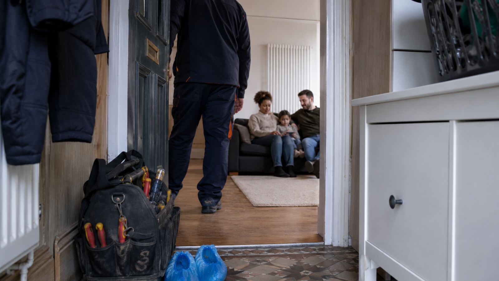 Heating engineer leaving after a repair while the family relaxes in the warm room
