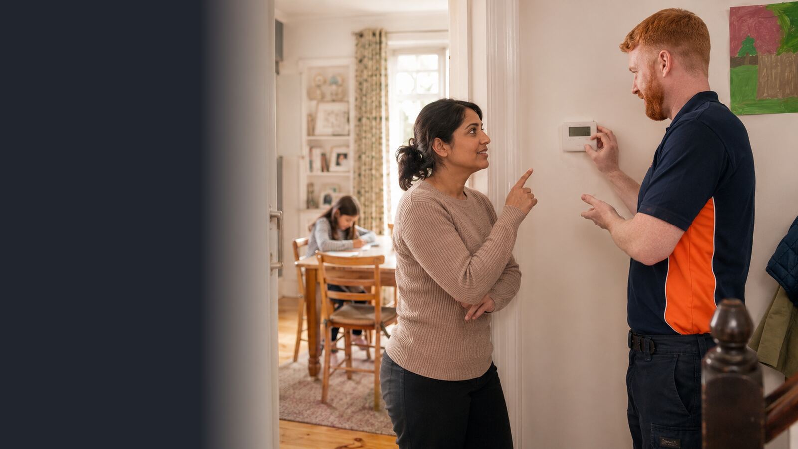 Heating engineer explaining thermostat controls to a mother in her family home