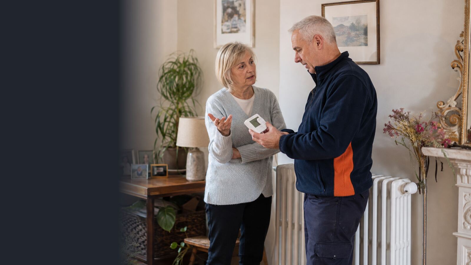 Heating engineer explaining thermostat settings to an older homeowner