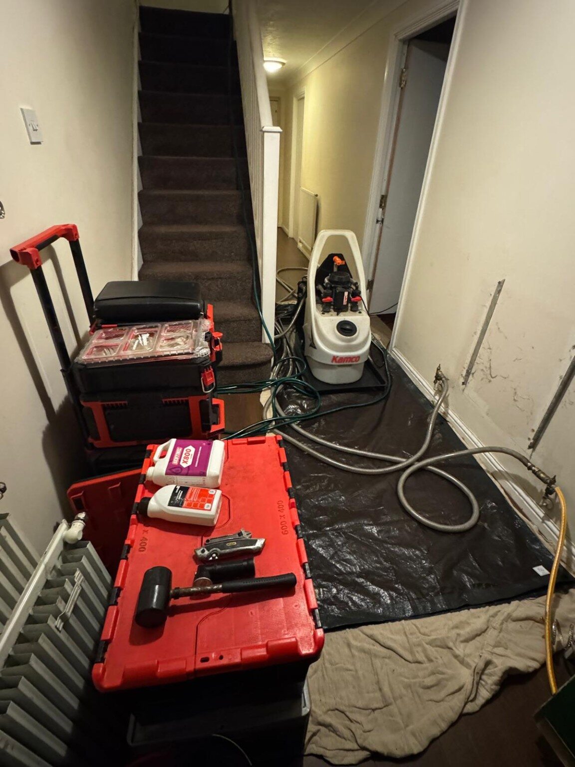 Floor protection and Kamco Clearflow CF90 power-flushing equipment set up in a customer's hallway